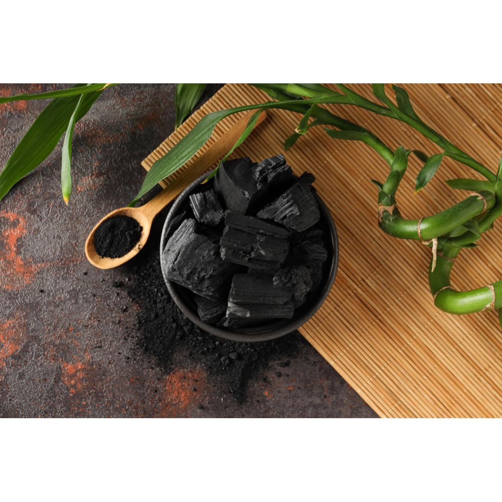 Shilajit gyanta és por fekete tálban, bambusz alátéten, zöld növényi dekorációval, természetes étrend-kiegészítő témájú blogcikkhez.